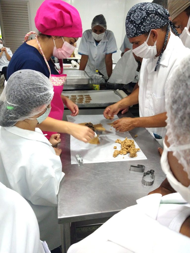 Profissionais na mesa no preparo de biscoito natalino