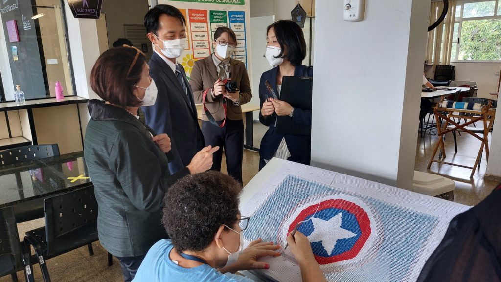 Embaixador do Japão olhando um trabalho de tapeçaria.